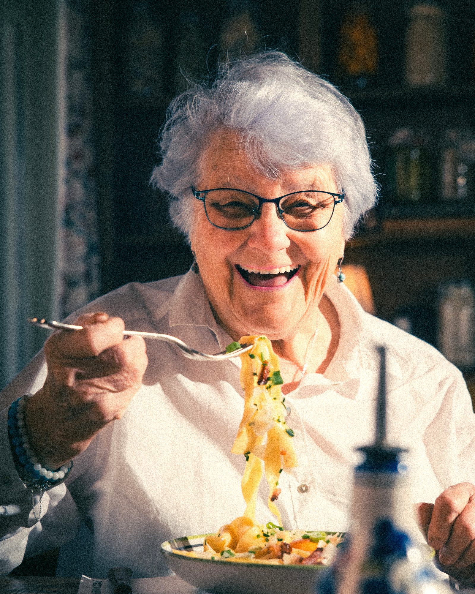 Une grand-mère rit devant son assiette de tagliatelle chez Pozzi Nonni