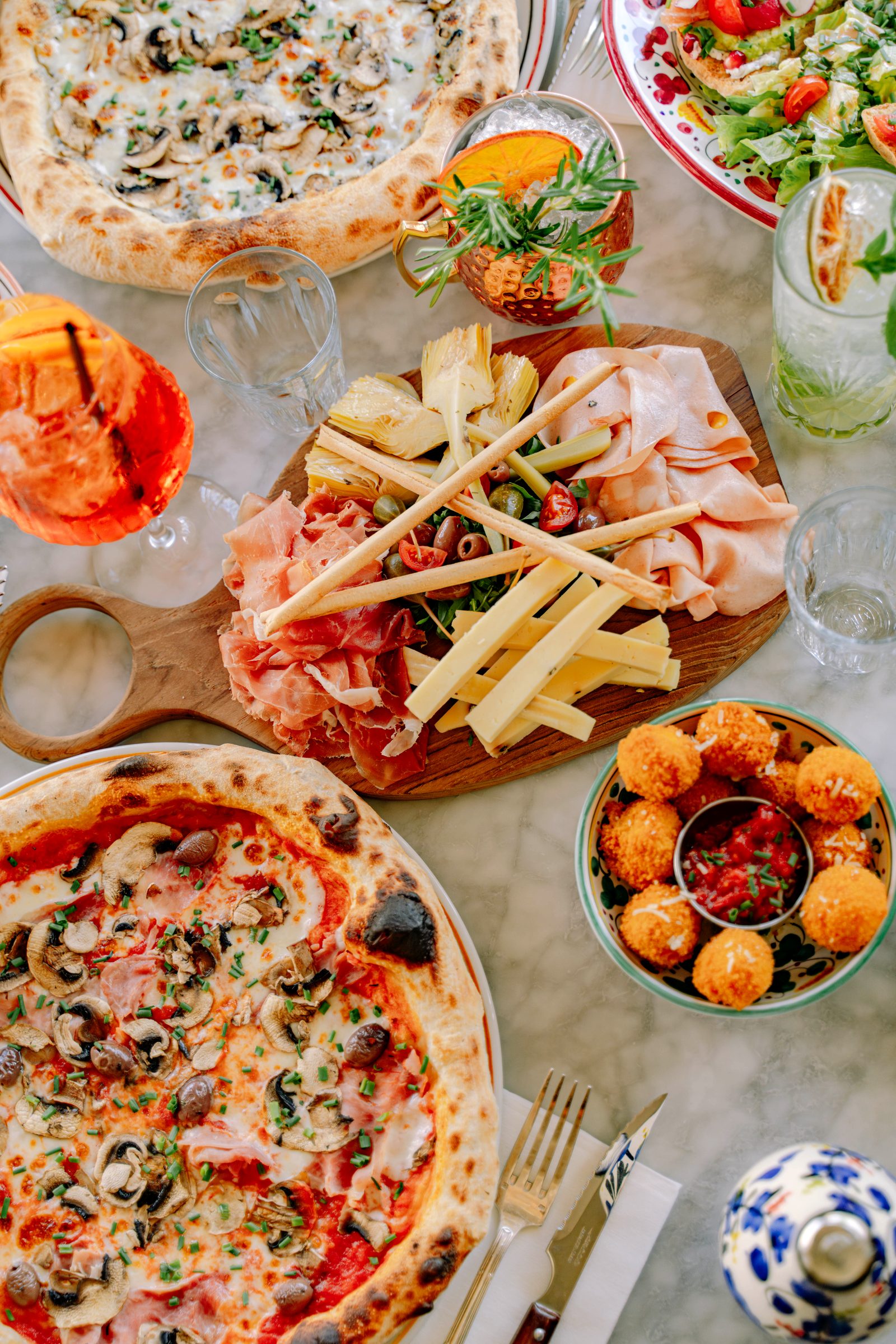 Une grande tablée de pizzas et d'antipasti partagés chez Pozzi Nonni